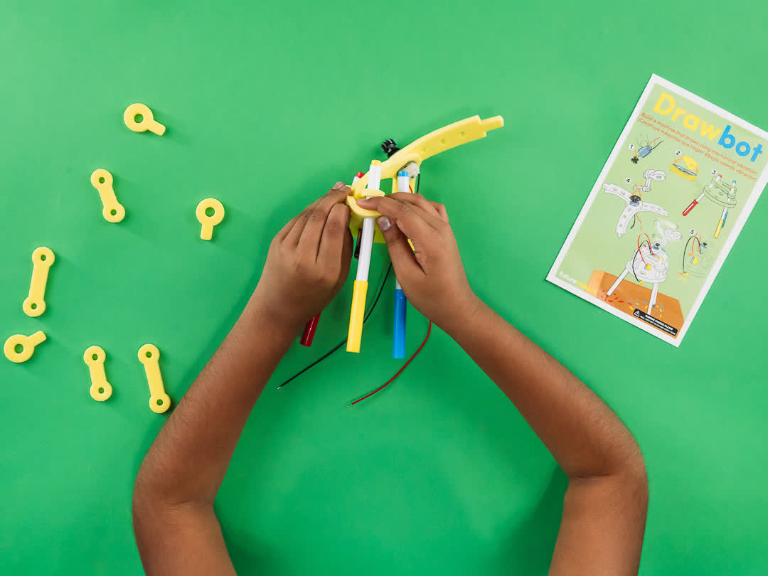 A child's hands building a Drawbot Spark